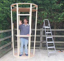 Greg is inside his creation, the framework of a large ice cream cone.